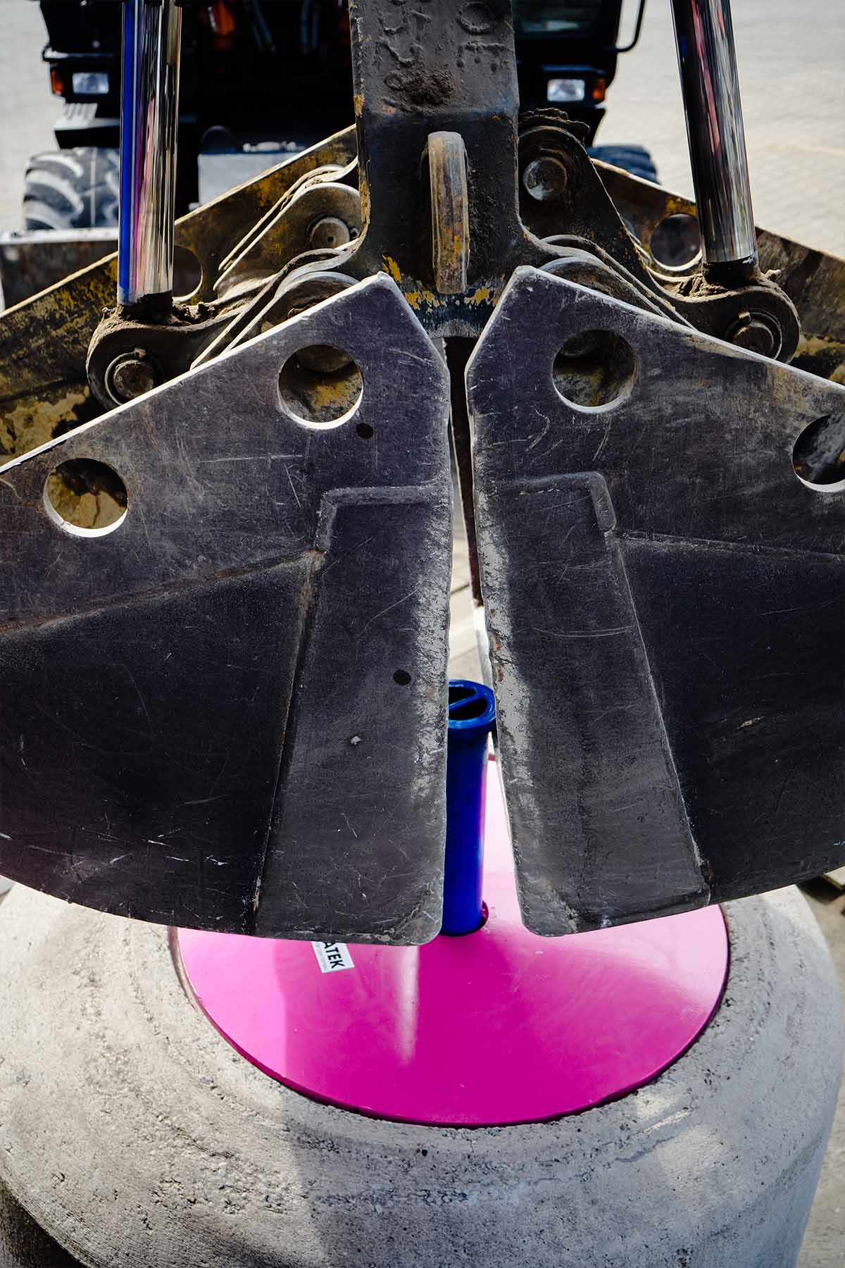 Der TIBATEK®-Asphaltdeckel  wird von einer Baggerschaufel über sein Zugrohr gegriffen